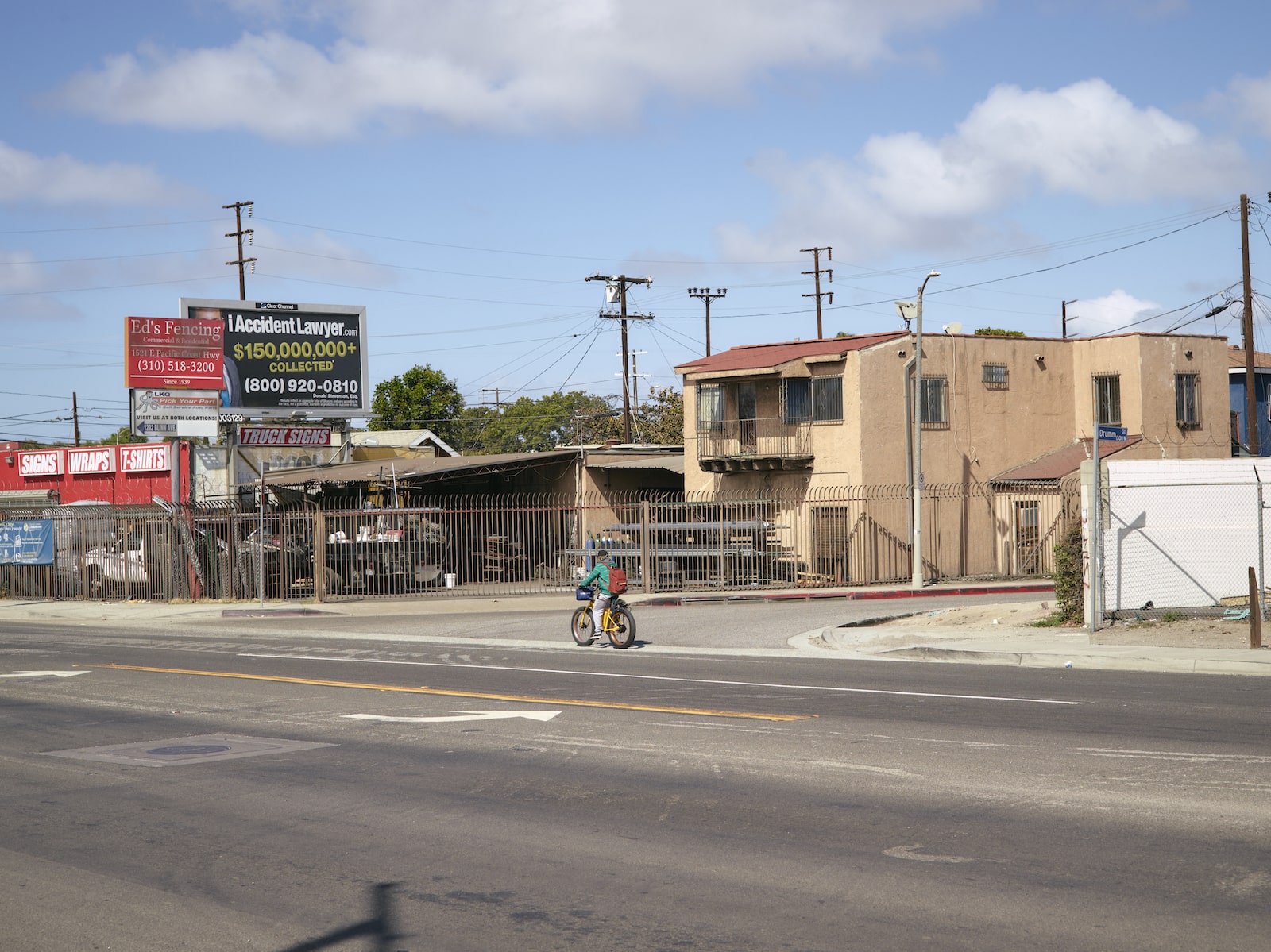a man on a bicycle rides past a billboard on a residential street