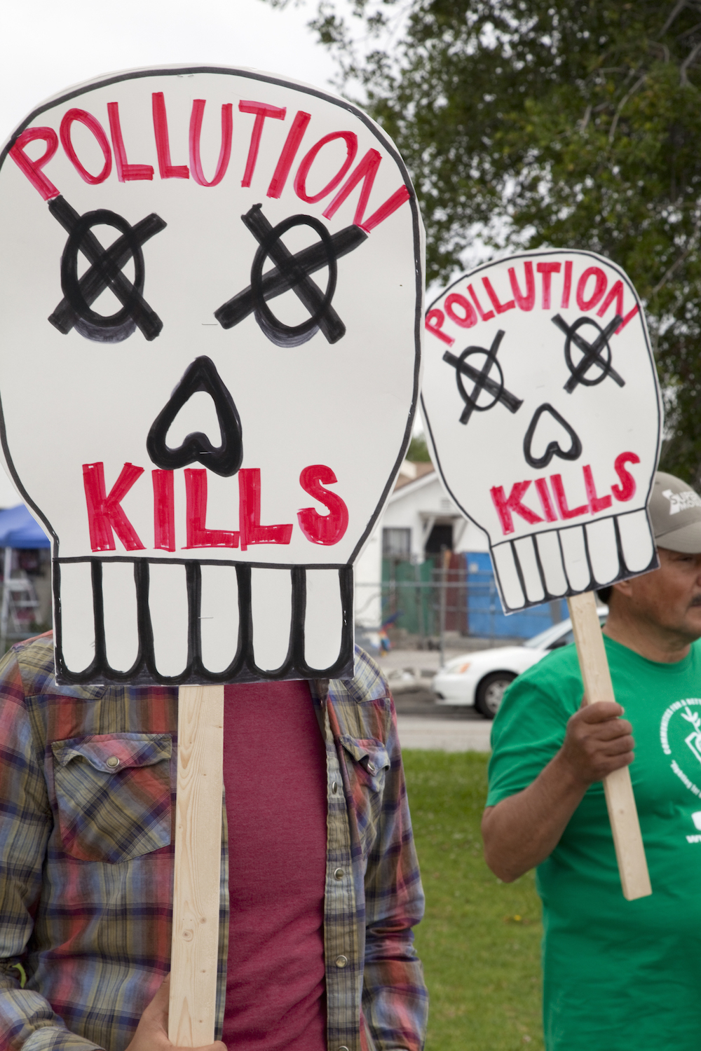 people hold signs shaped like skulls that say pollution kills