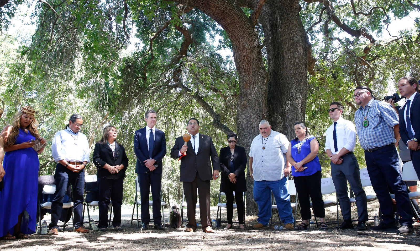 Tribal leaders and Governor Newsom stand in a line under a tree