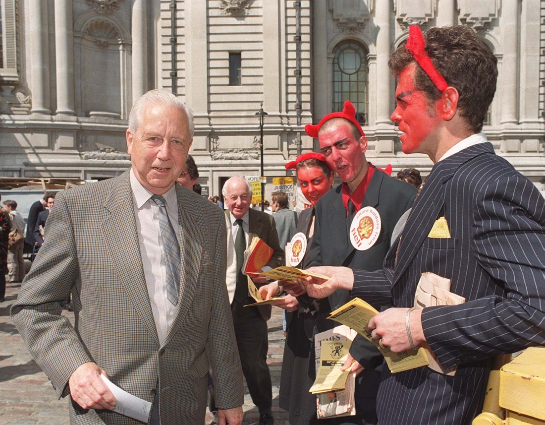 Protesters in devil costumes next to a man in a suit.