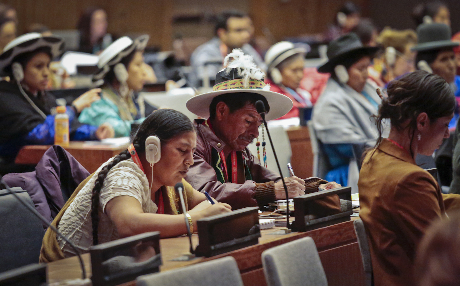 Indigenous representatives listen on headsets and take notes at the UN