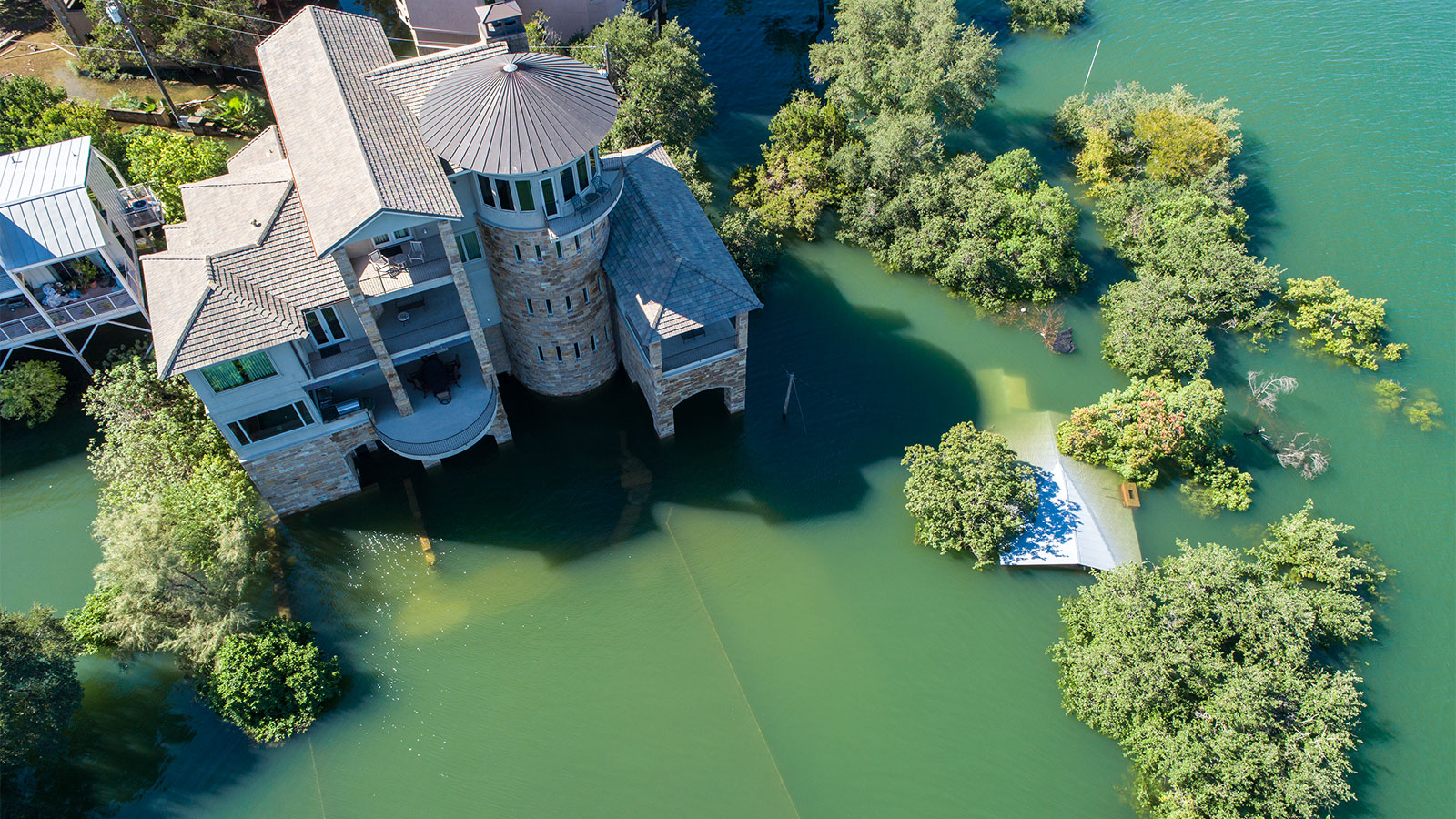 Aerial view of a mansion and trees surrounded by floodwater