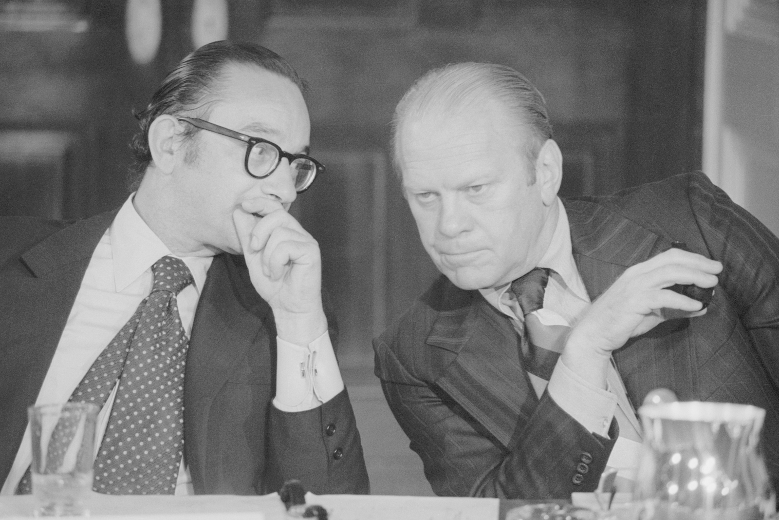 a black and white photo of two men talking