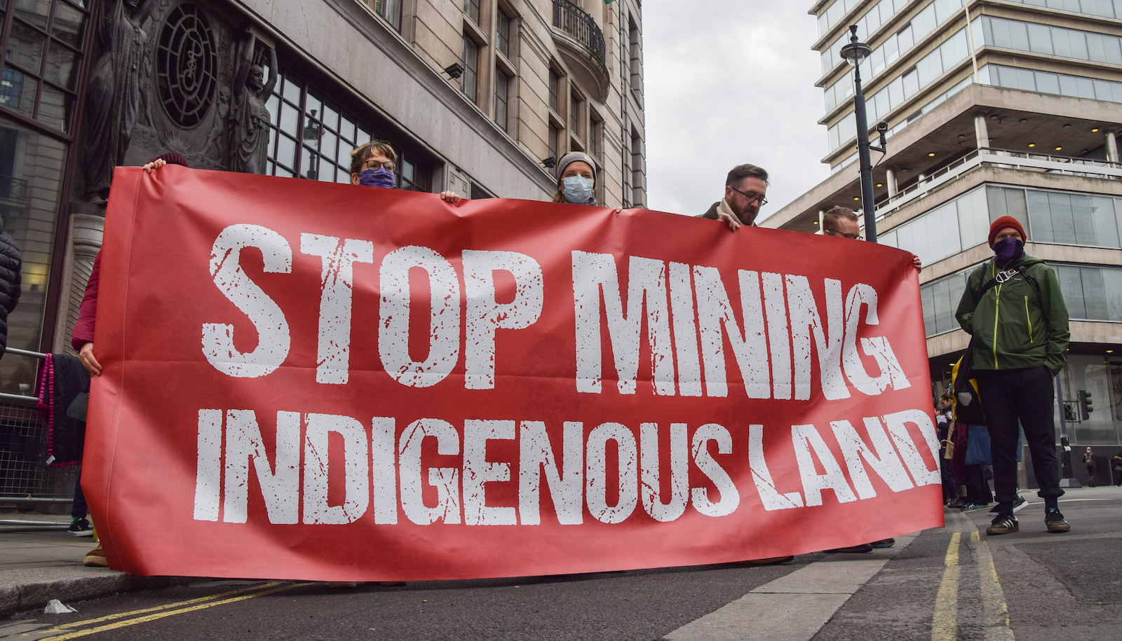 Protestors hold up a sign that says stop mining indigenous land