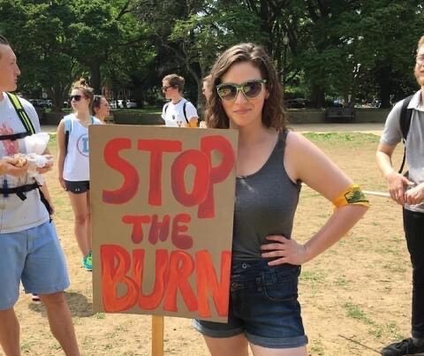 a woman with a sign reading “Stop the Burn”