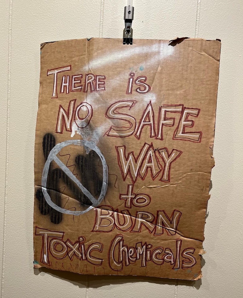 A sign reads: “There is no safe way to burn toxic chemicals”
