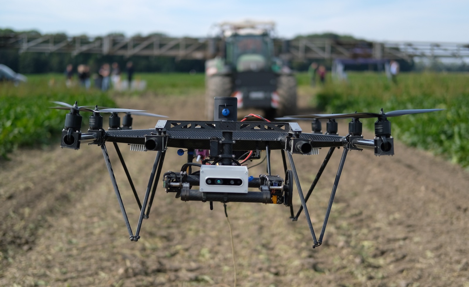 A drone hovers in front of a tractor with fertilizer equipment during a 2021 technology show in a field in northern Saxony. A multispectral camera on the drone detects the fertilizer needs of the arable plants.
