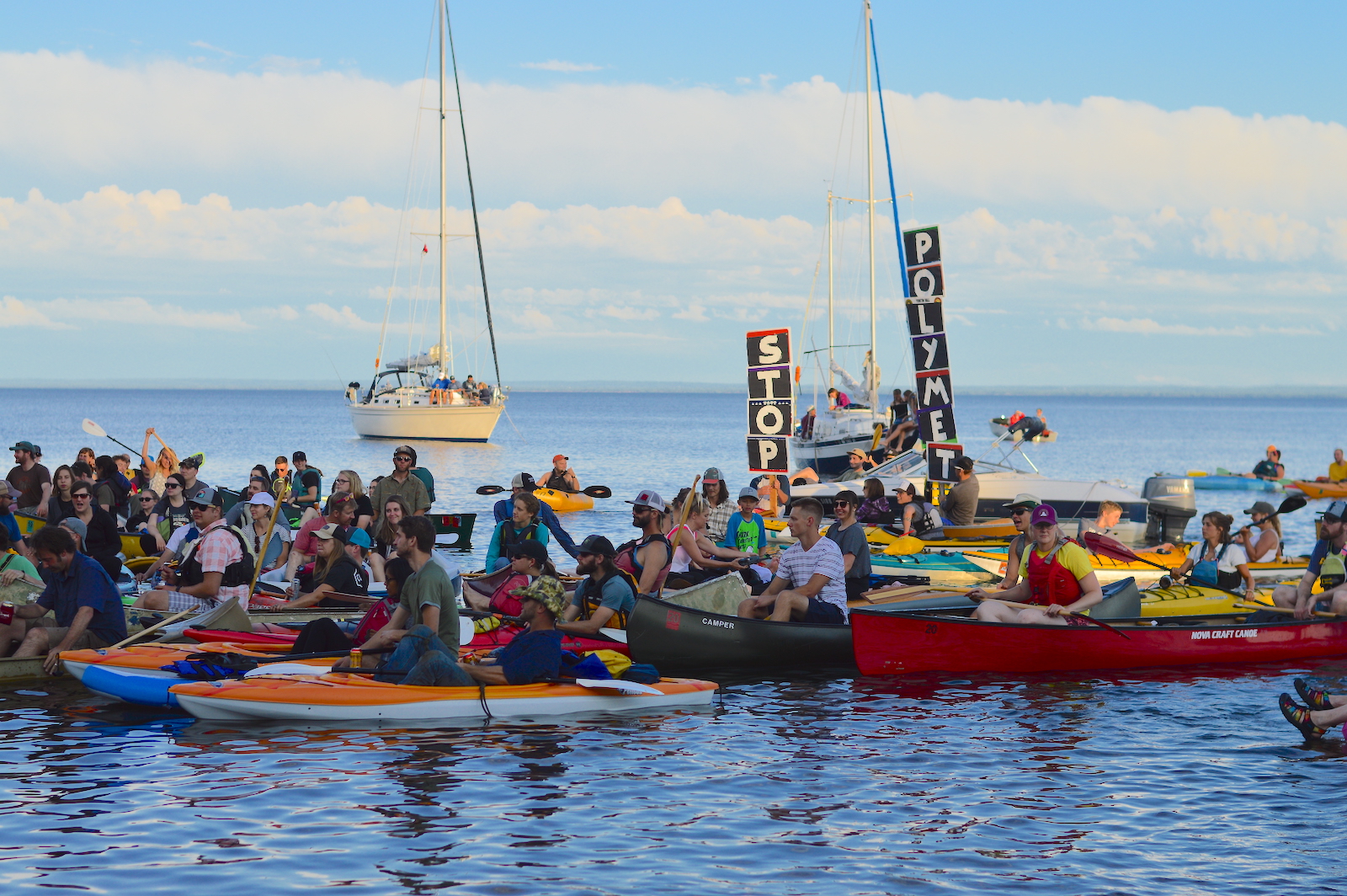 Protesters on boats hold up signs proclaiming "STOP POLYMET".