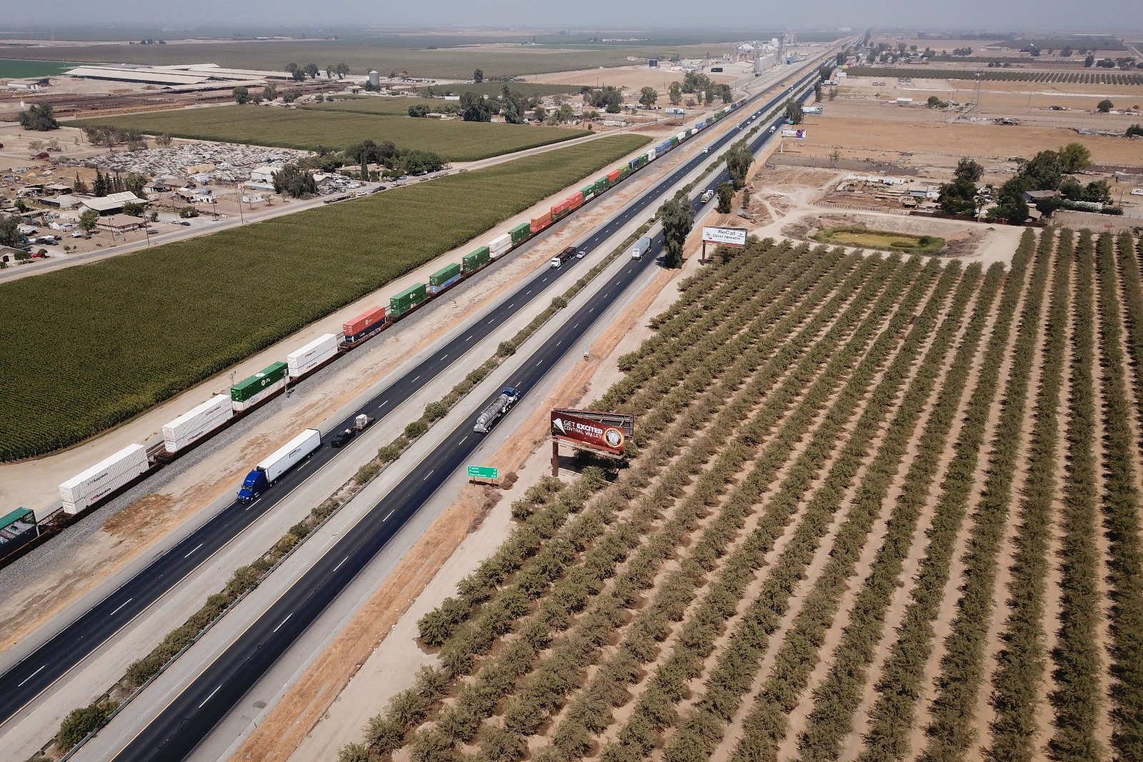 Vehicles drive past farmland and a freight train though Tulare County in the Central Valley near Pixley, California, in 2021.