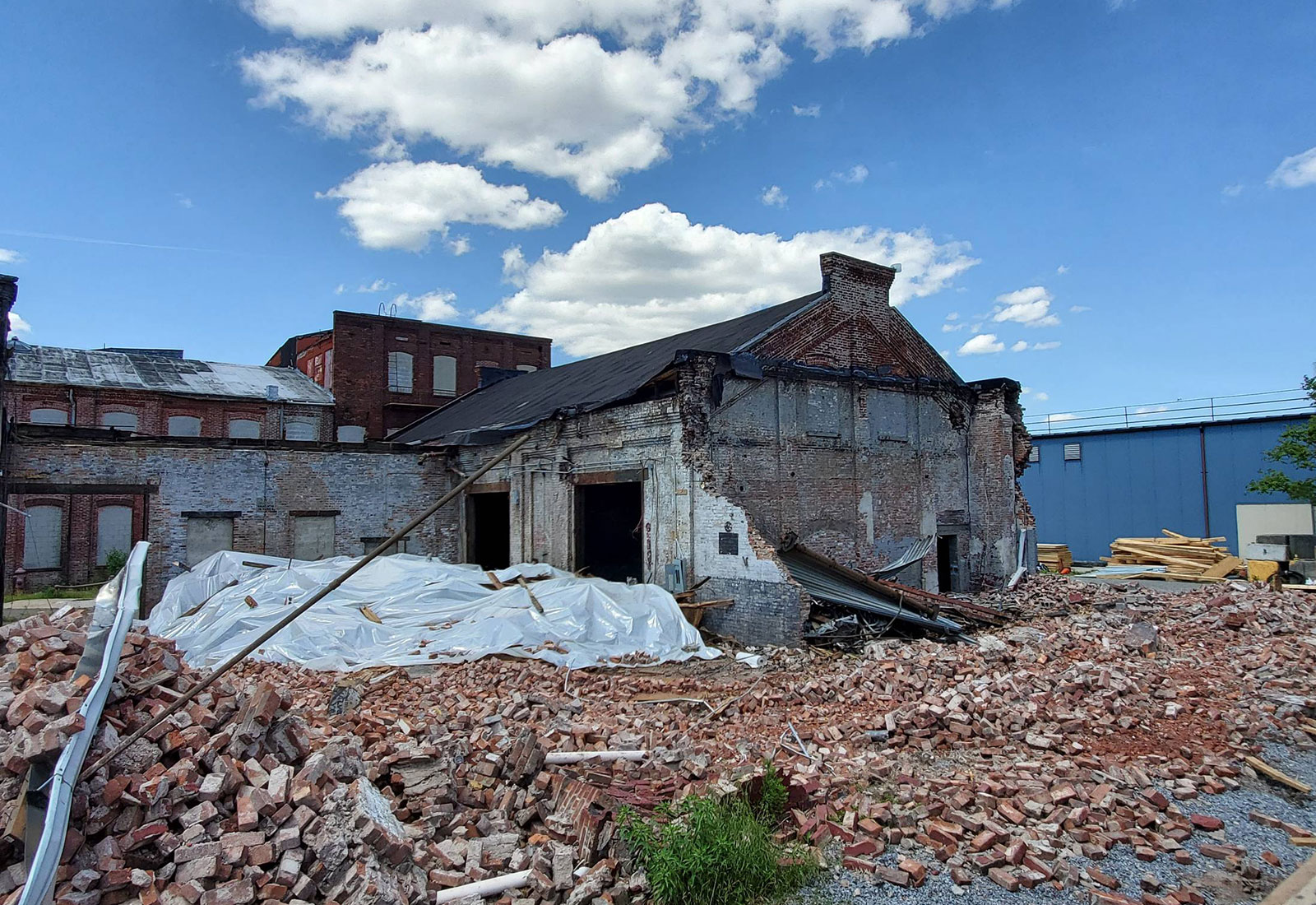 Partially demolished historic factory with some buildings still standing surrounded by piles of brick and shards of wood