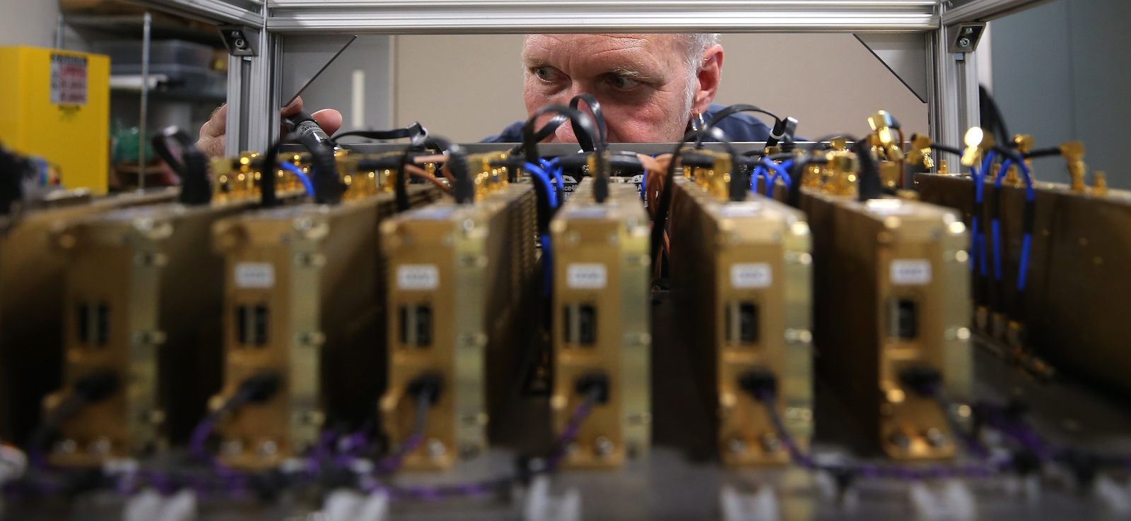 a man's eyes are visible peeking over rows of electrical equipment