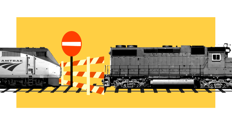 Amtrak train and freight train separated by traffic barrier and no entry sign