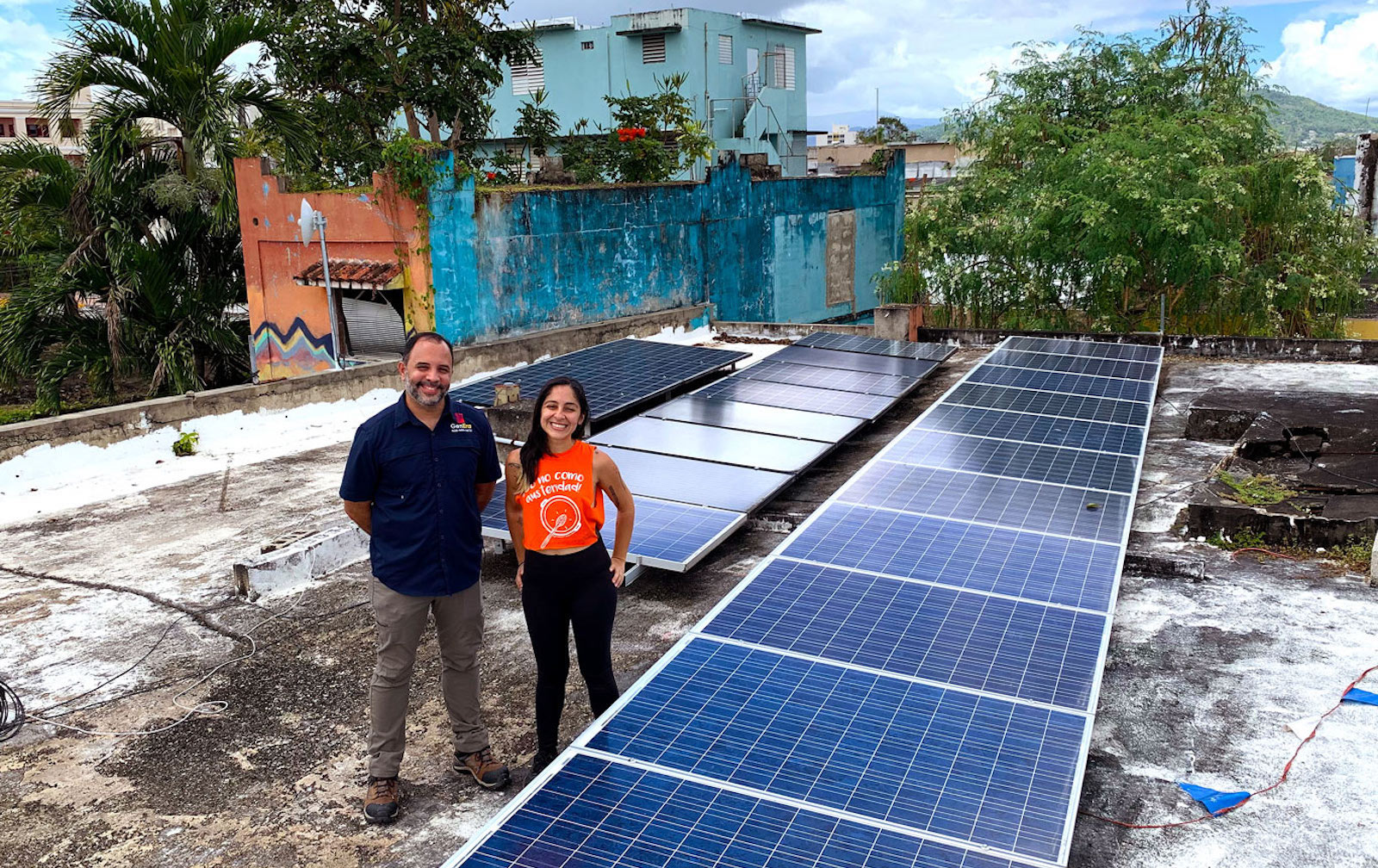 Saúl González, a la izquierda, y Marisel Robles ayudan a mantener el sistema fotovoltaico en el techo del Centro de Apoyo Mutuo en Caguas, Puerto Rico