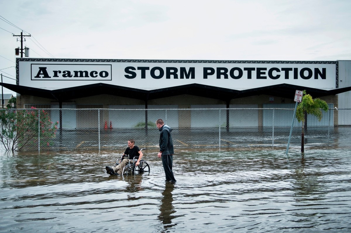 Two men in a flooded street before a building that says 