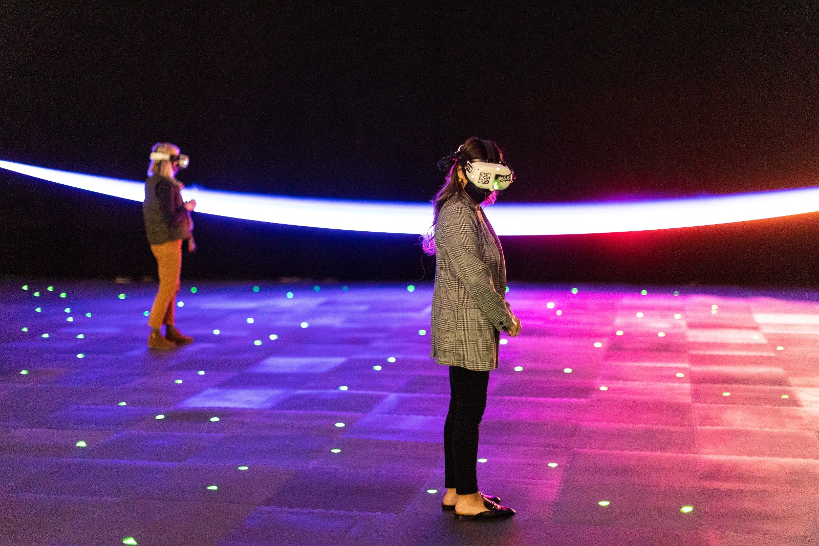 People wearing headsets stand on a purple gradient floor against a dark background with a white crescent across it.