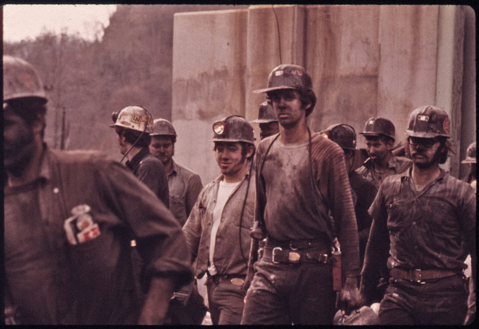 1974 photo of group of coal miners covered dirt and coal dust leaving a mine