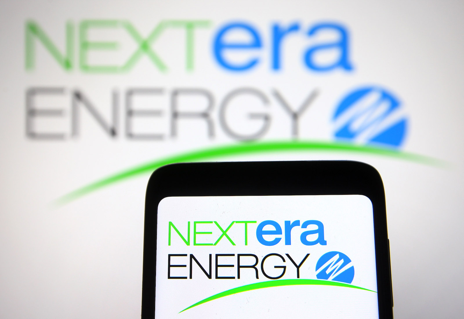 NextEra logo on a phone and slightly blurred in background