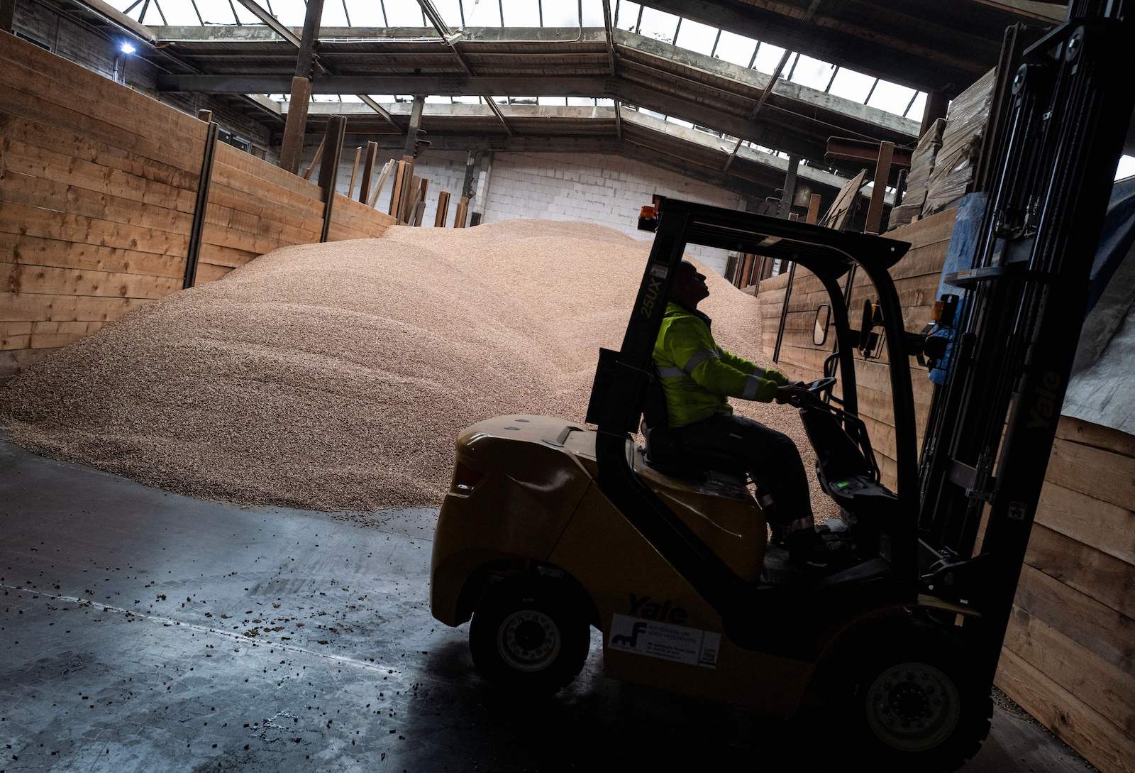 a person drives heavy machinery near a large pile of wood pellets