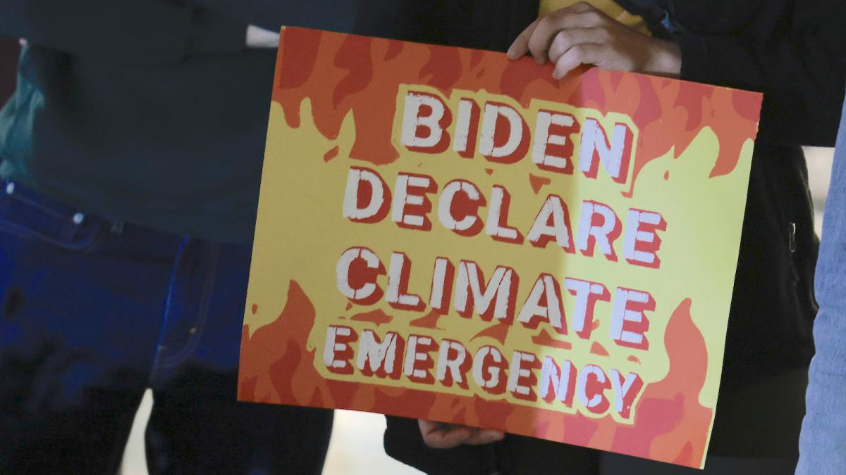 A protester holds a sign saying "Biden Declare Climate Emergency"