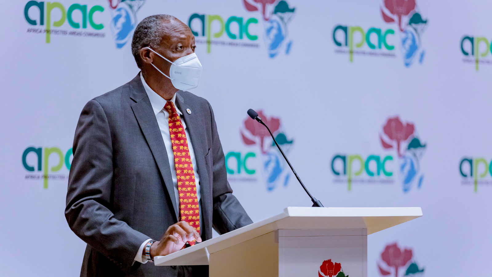CEO of African Wildlife Foundation, Kaddu Sebunya, speaks at a podium; a backdrop with Africa Protected Areas Congress's logo on it in the background