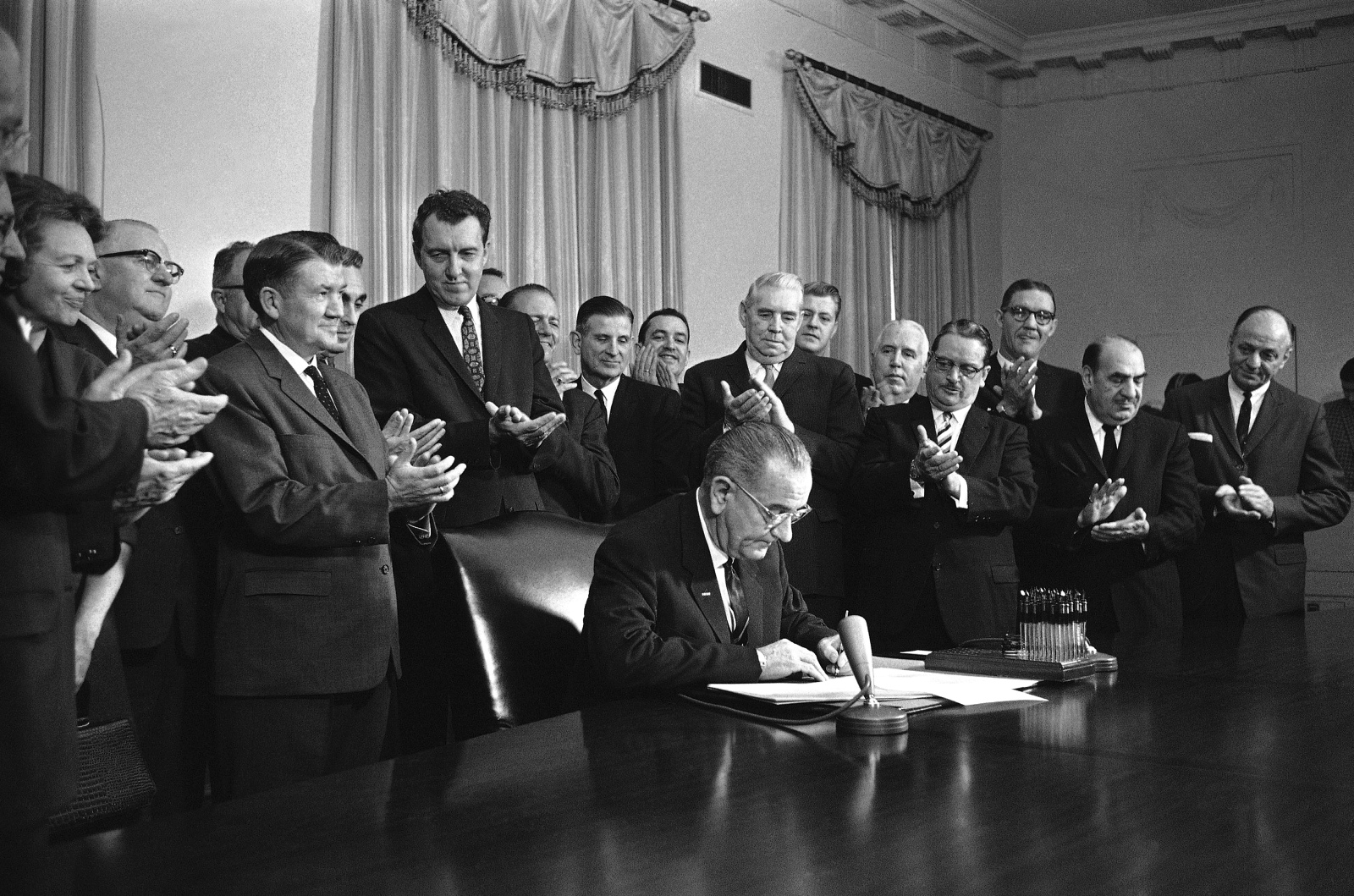 a black and white photo of the president signing a document