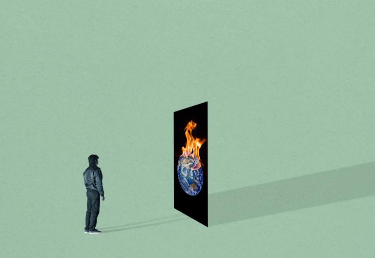 A person stands in front of a panel showing the Earth on fire