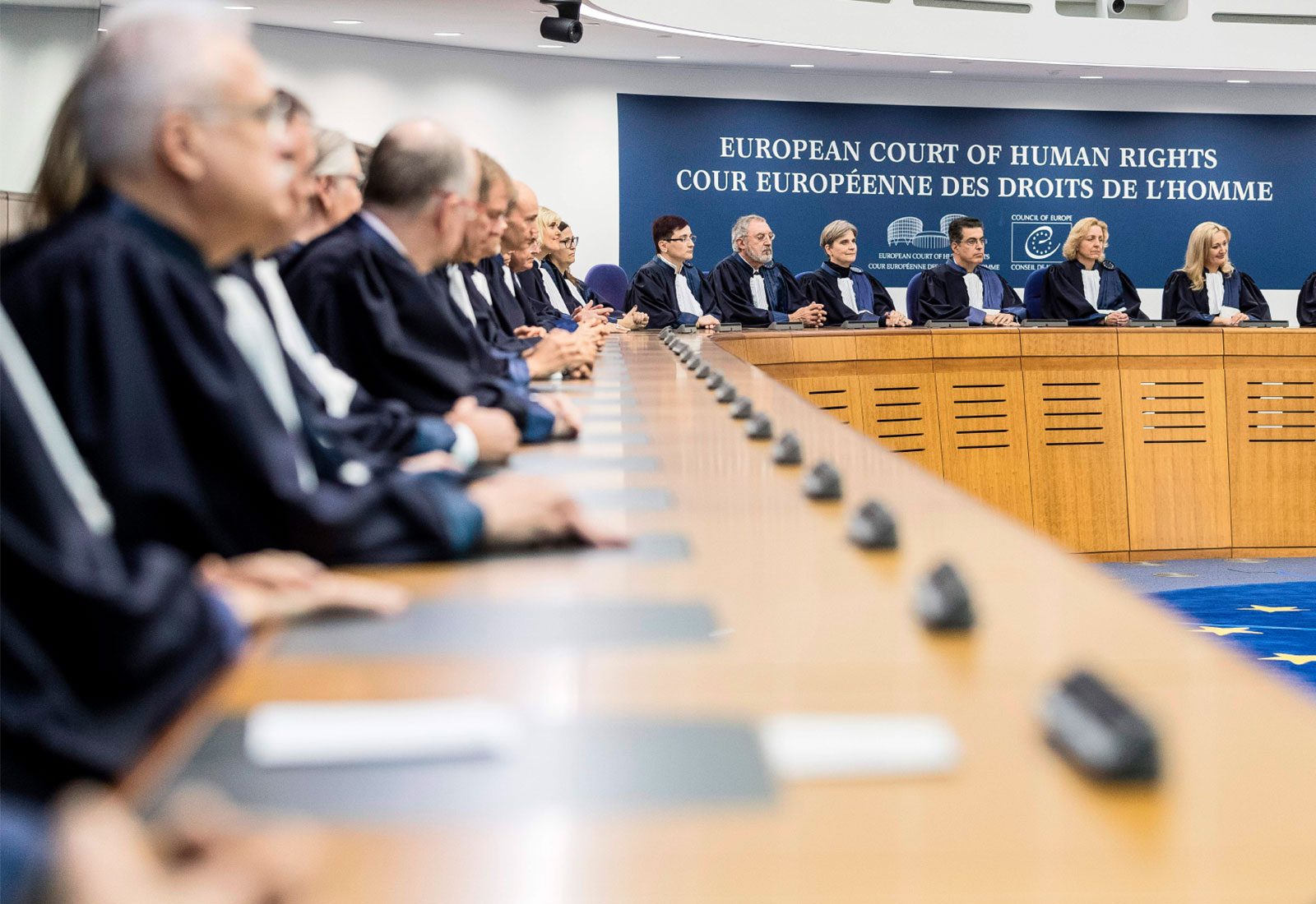 Large group of judges sitting at connected podiums in the European Court of Human Rights