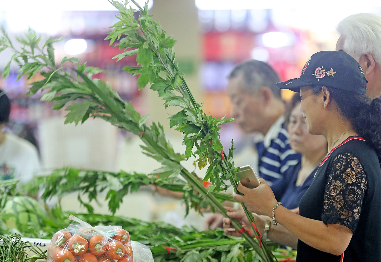People holding long stalks of mugwort in a grocery store in Hangzhou, Zhejiang Province of China