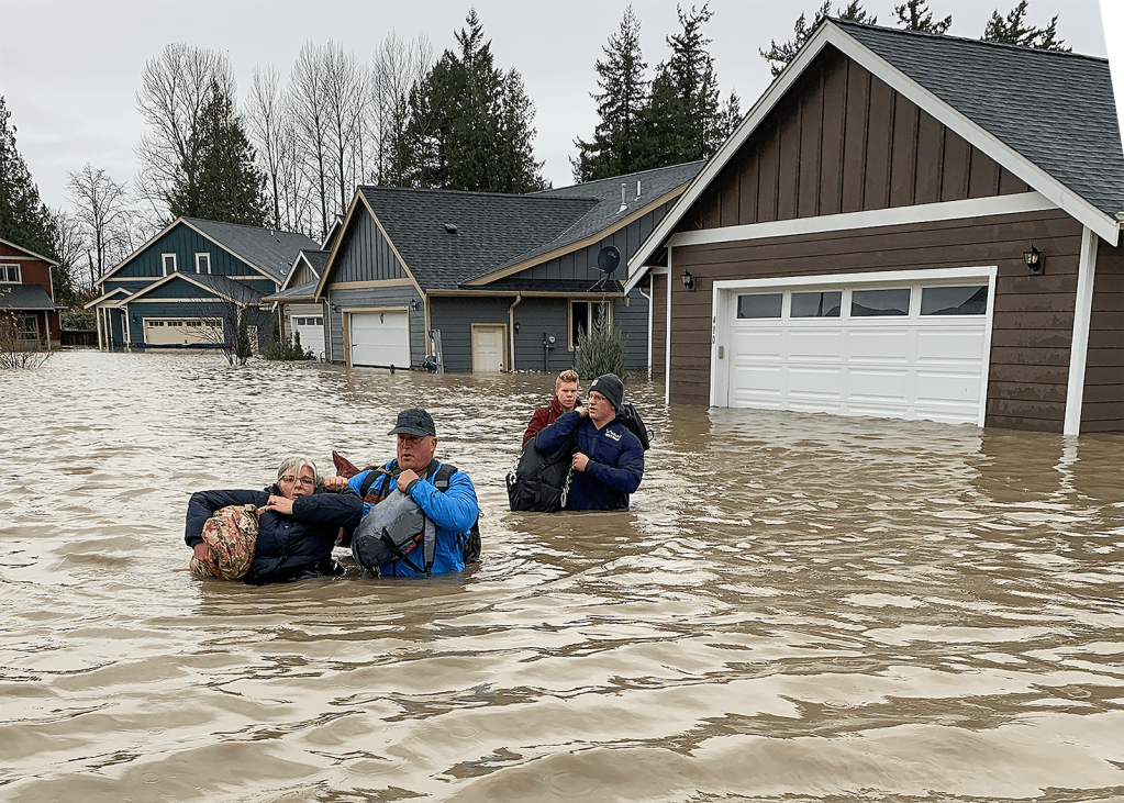 Residents of Everson traverse chest-high water to leave their homes.