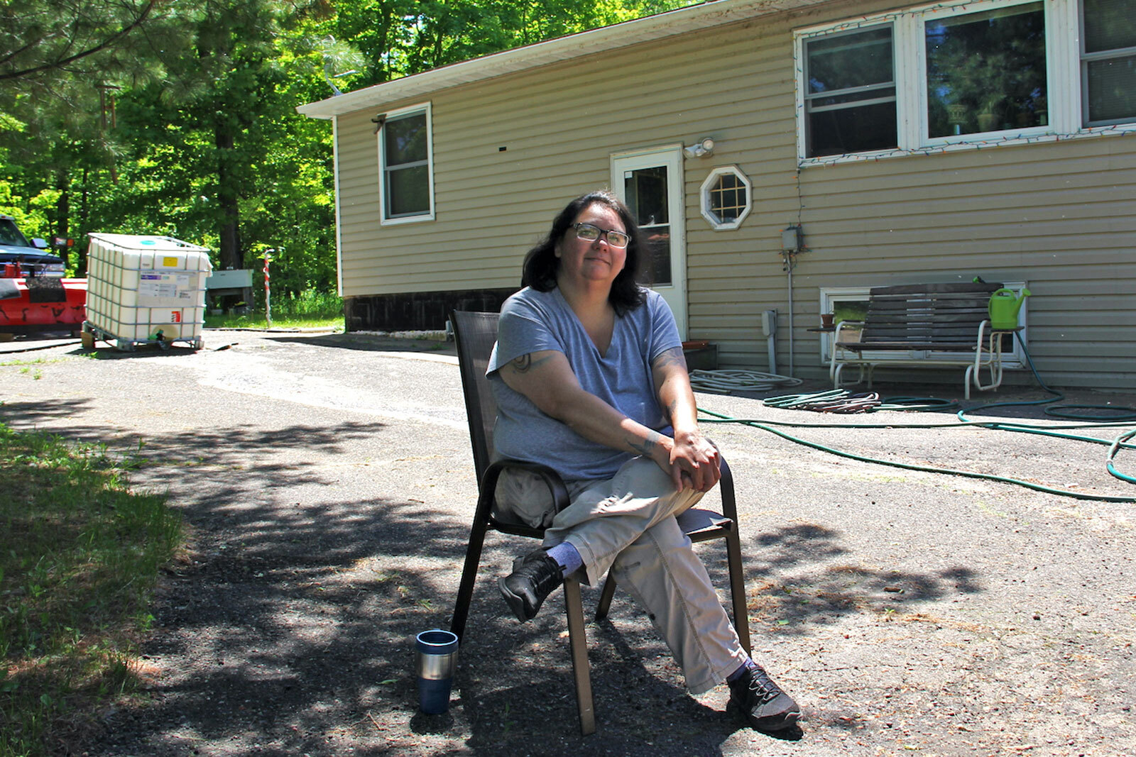 a woman sits in a chair in front of a house