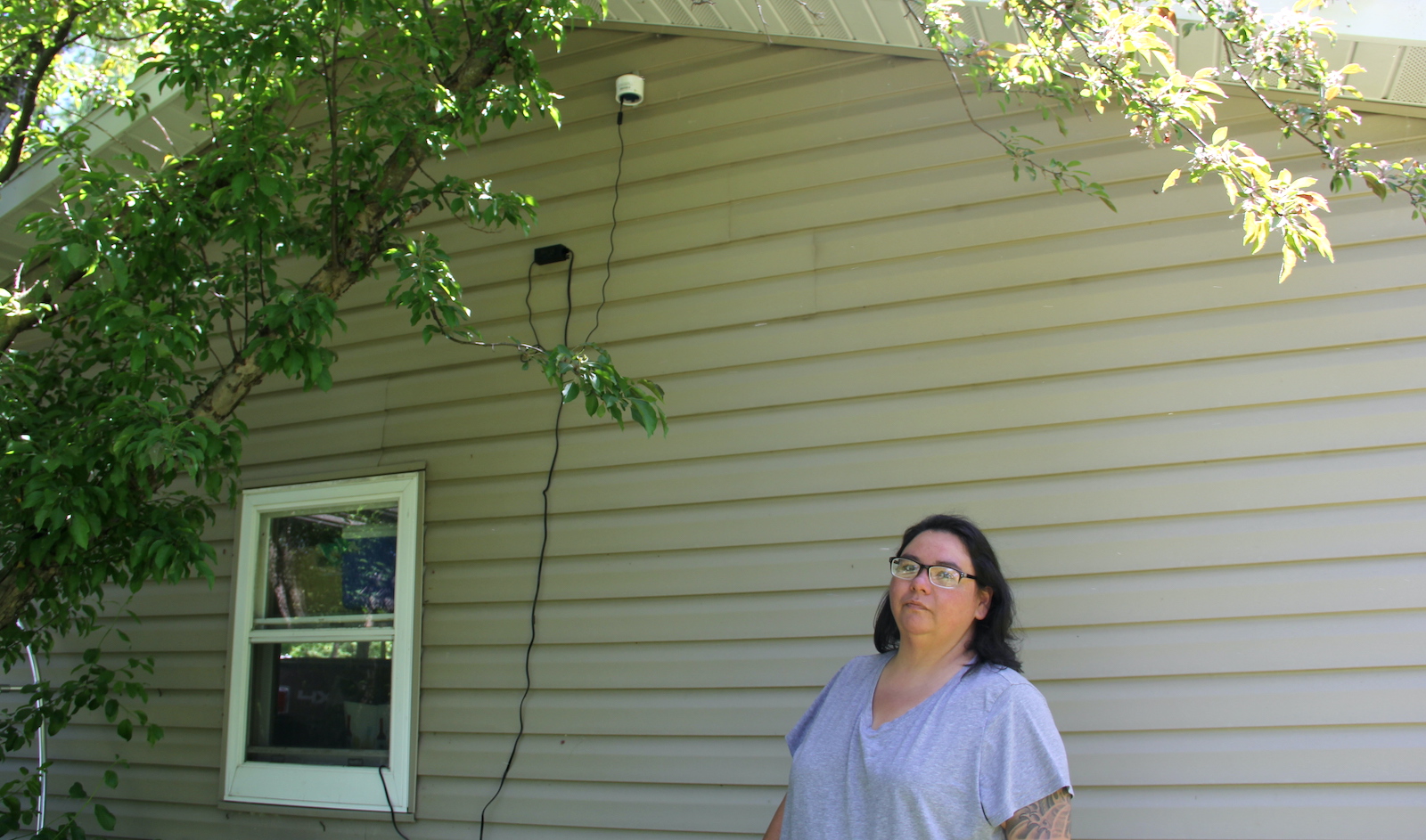 a woman stands underneath a white cannister attached to a house
