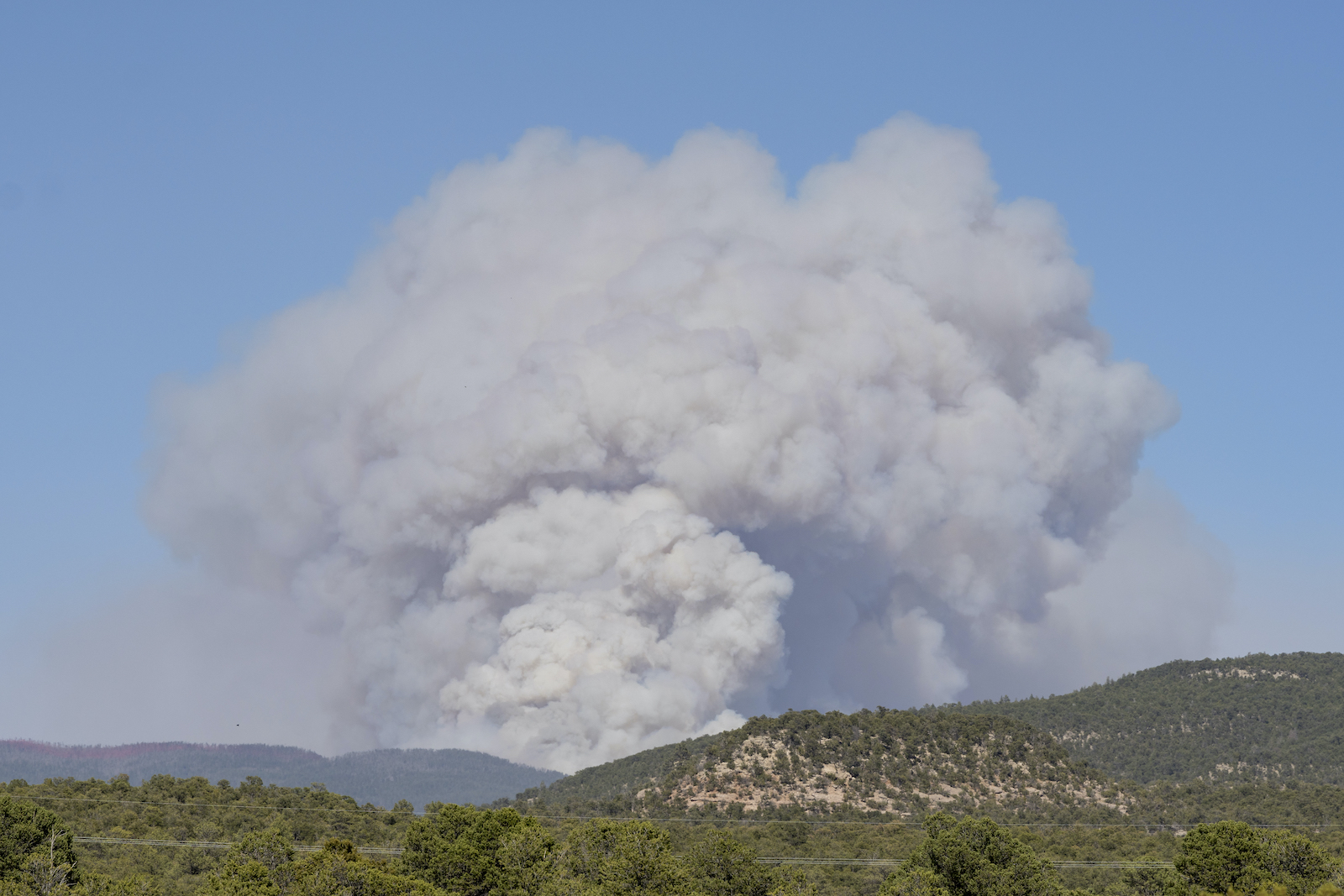 a huge cloud of smoke rises above a desert landscape