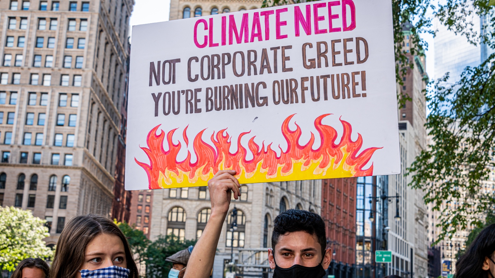 a sign saying "climate need not corporate greed, you're ruining our future"