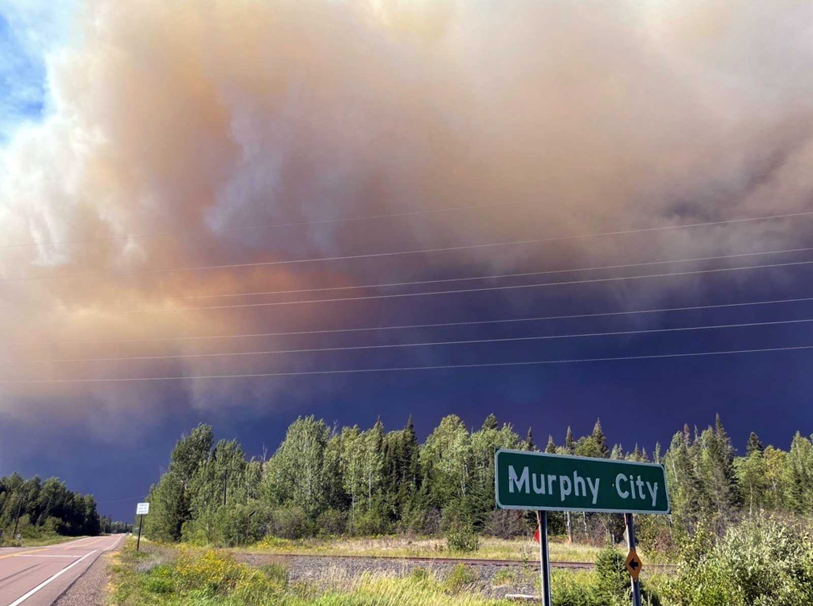 a large purple and black cloud of smoke swirls over a green sign that says Murphy City