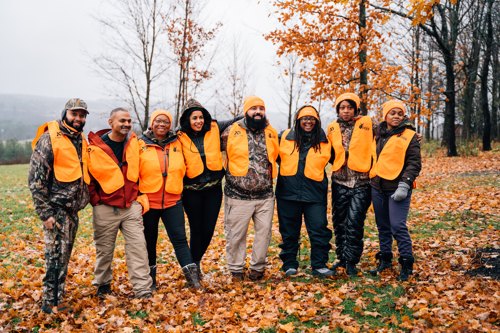 a group of people in hunting gear gather for a group photo