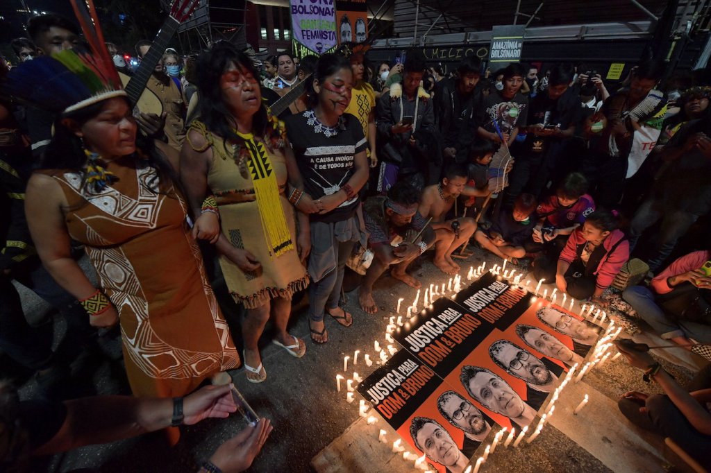 Indigenous people stand over a candlelit memorial