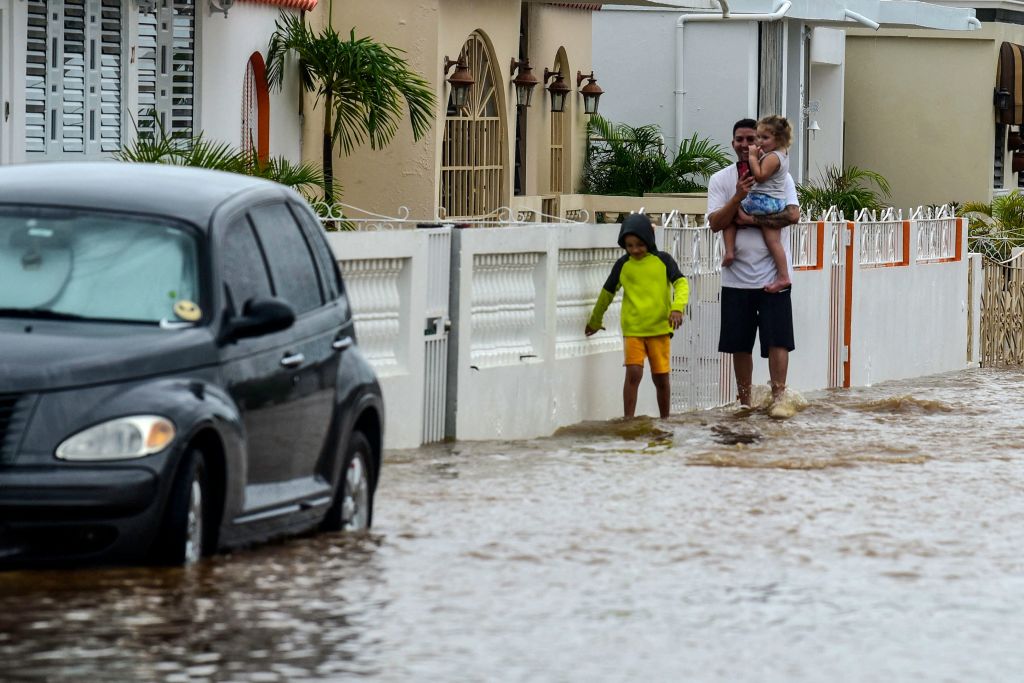 Man and two children walk on flooded road