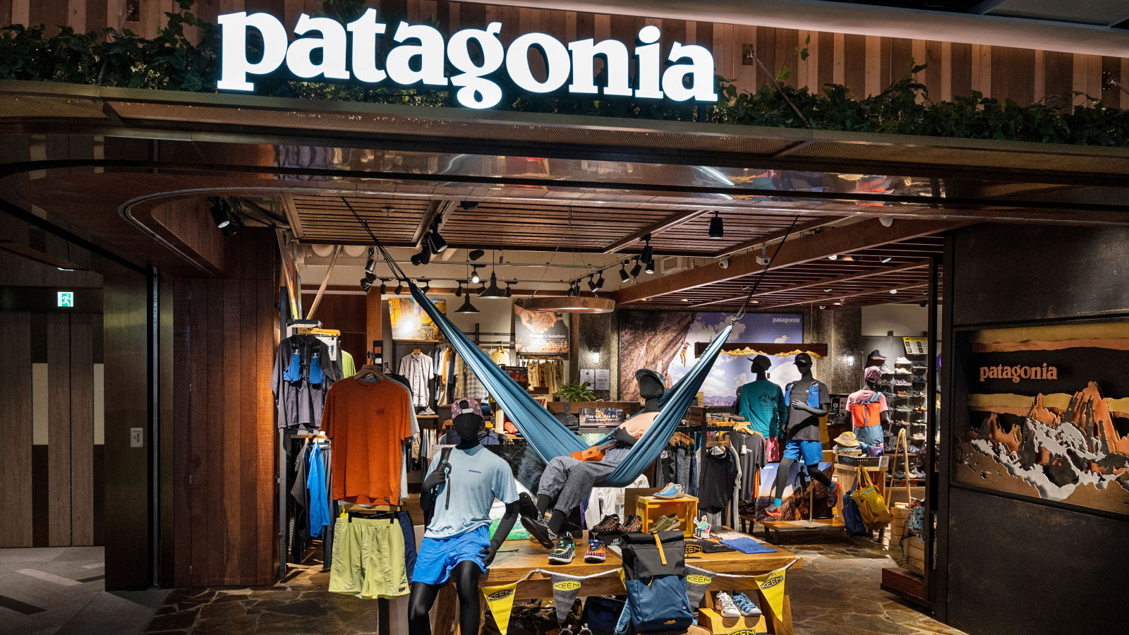 A Patagonia storefront featuring mannequins sitting and lounging in a hammock amongst clothing and gear displays