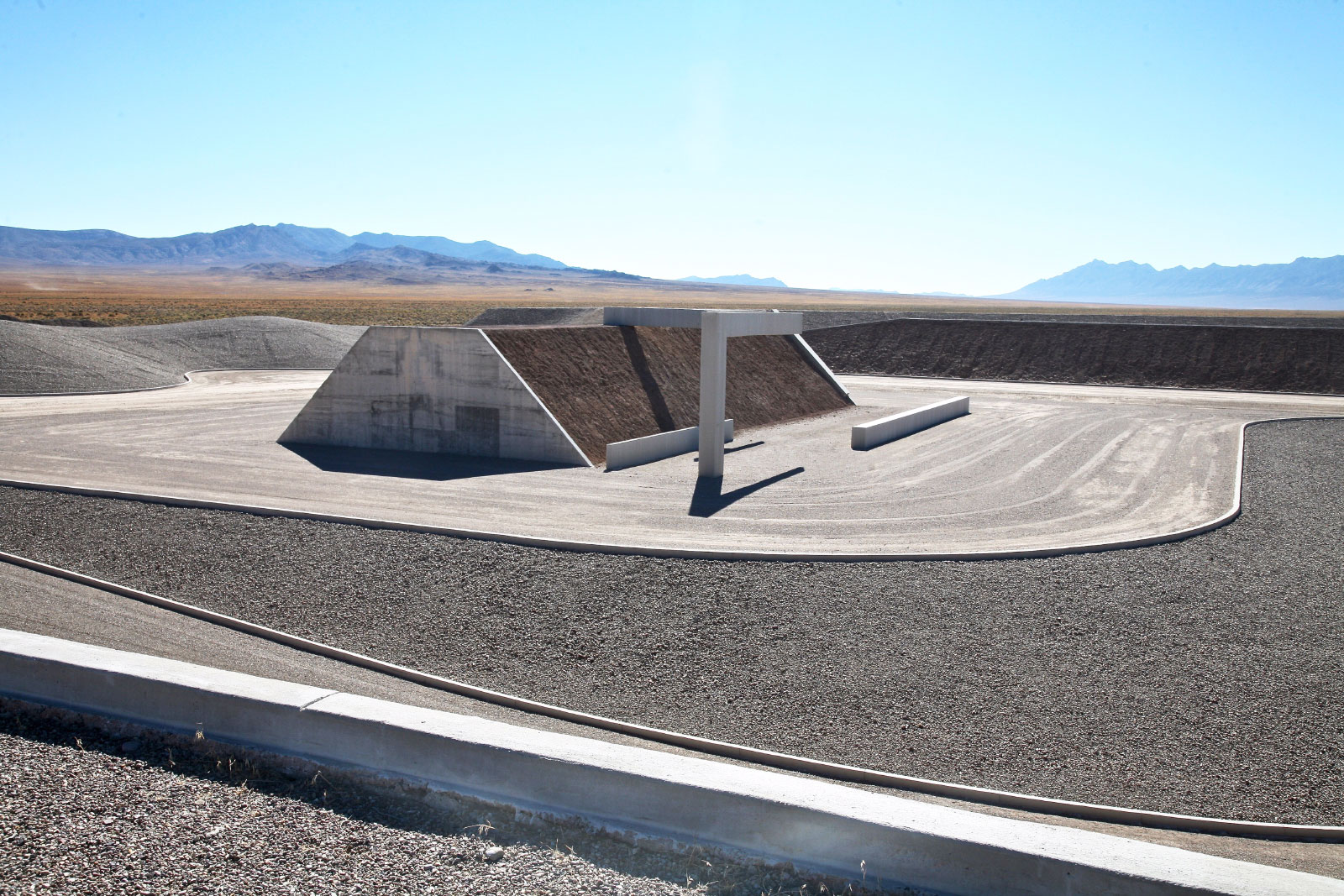 a trapezoidal prism made of stone stands on a desert landscape