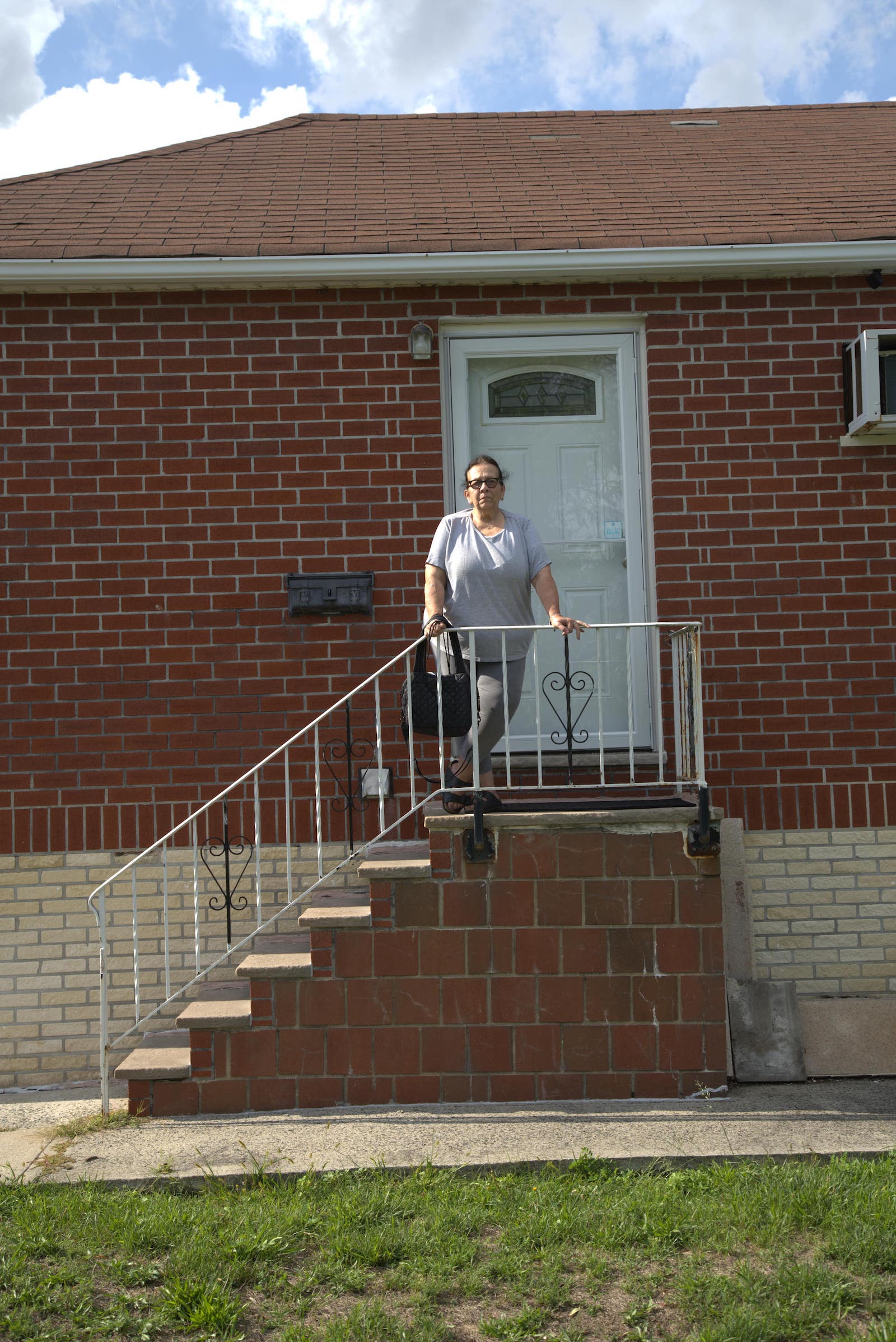 a woman in a t-shirt and jeans on the stairs of a brick house
