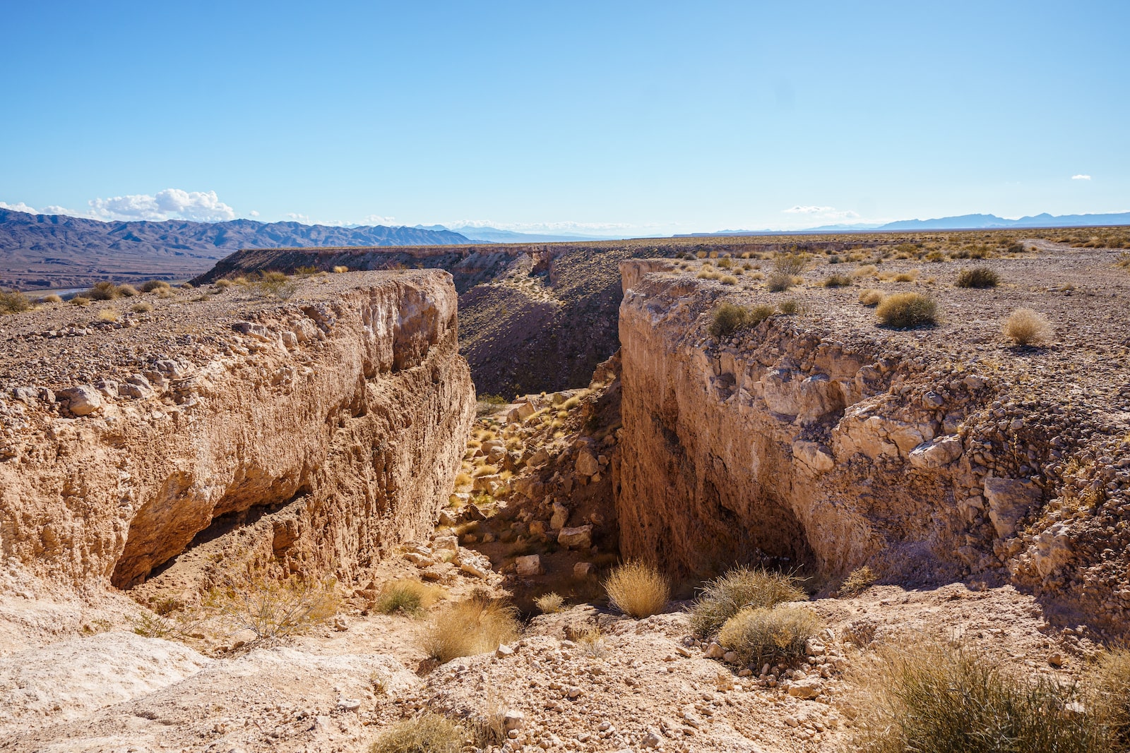 A desert scene with a narrow channel opening between two large sections of rock.
