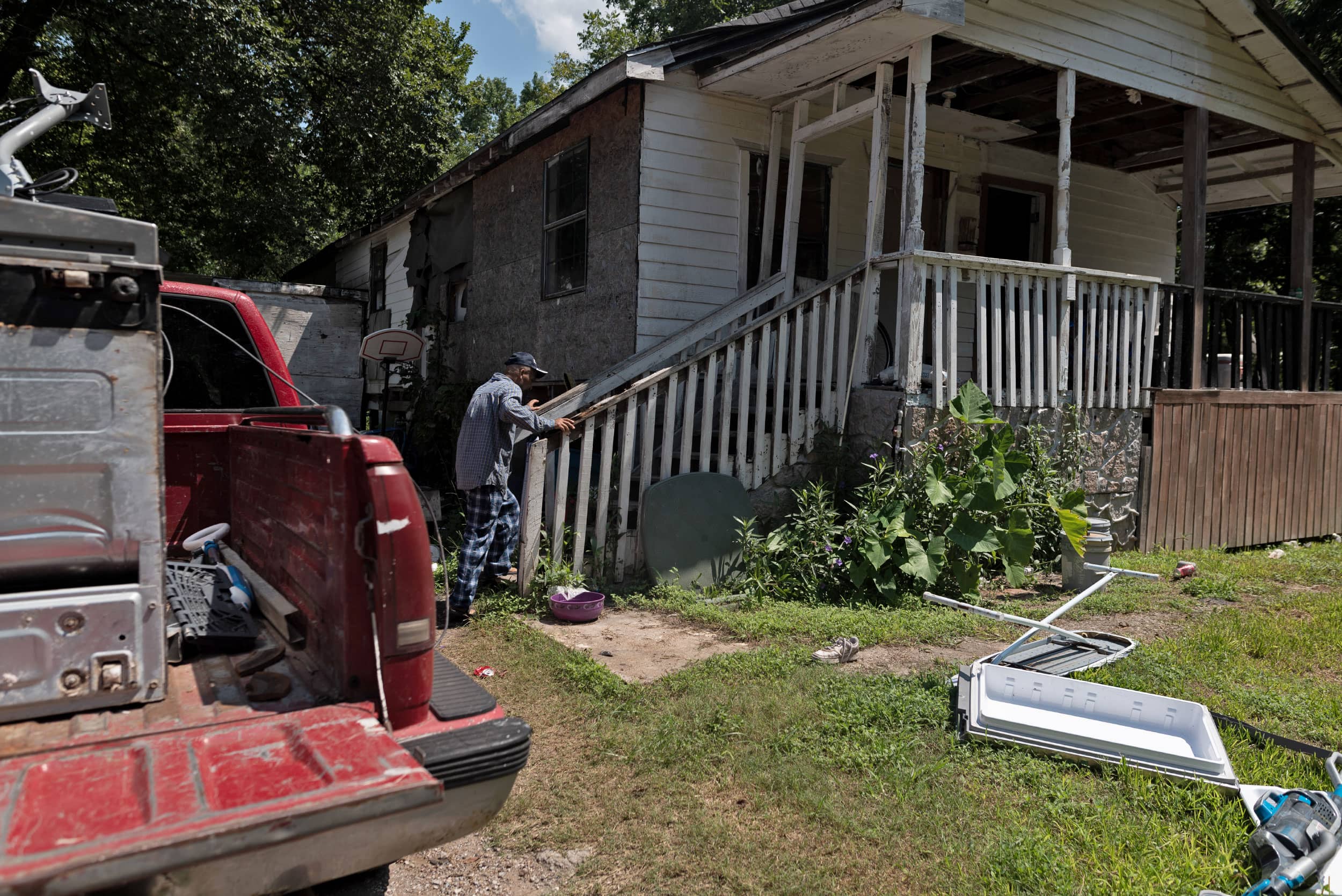A man walks up the steps to his home with a truck parked out front