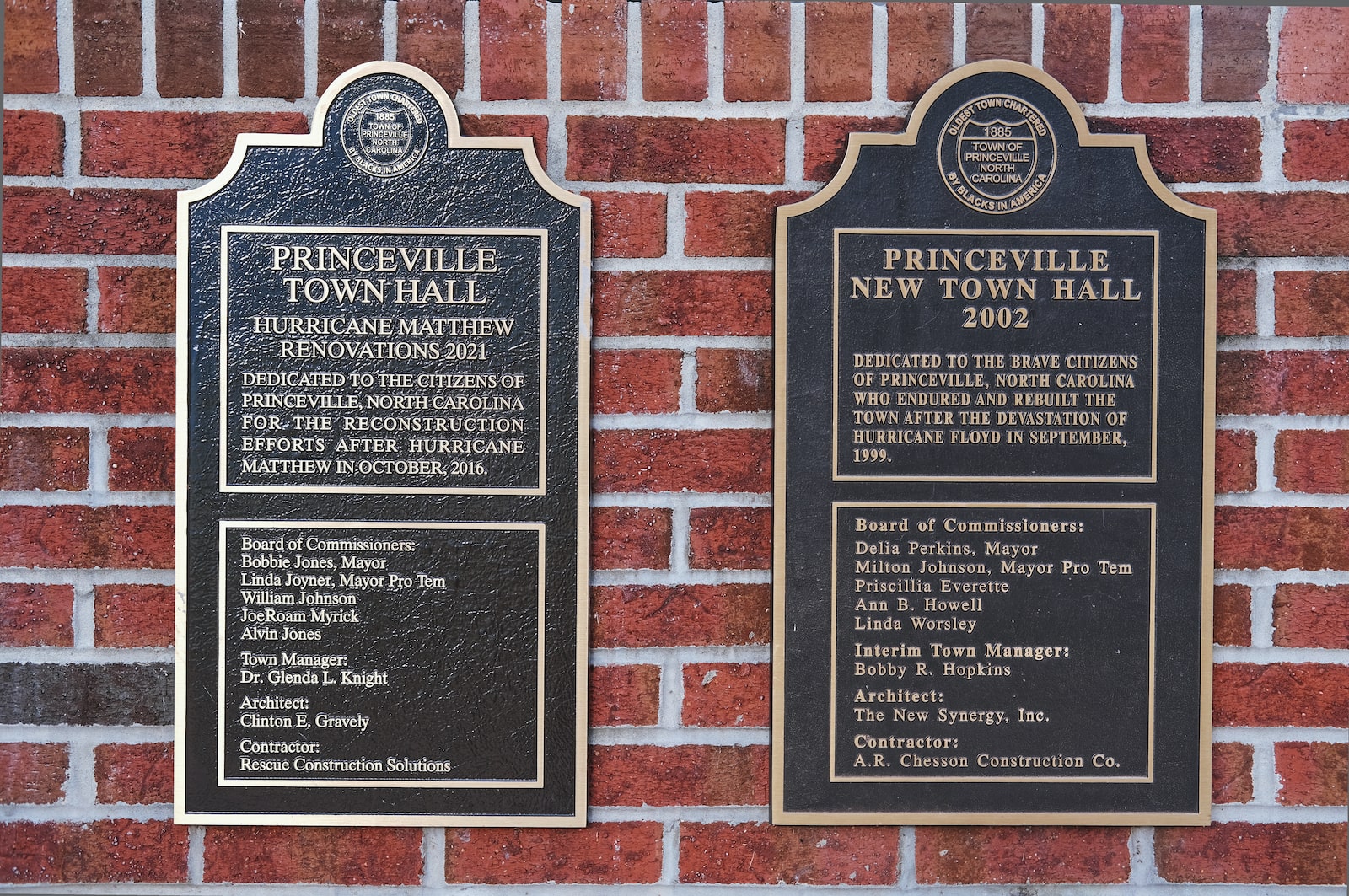 two plaques on a brick wall