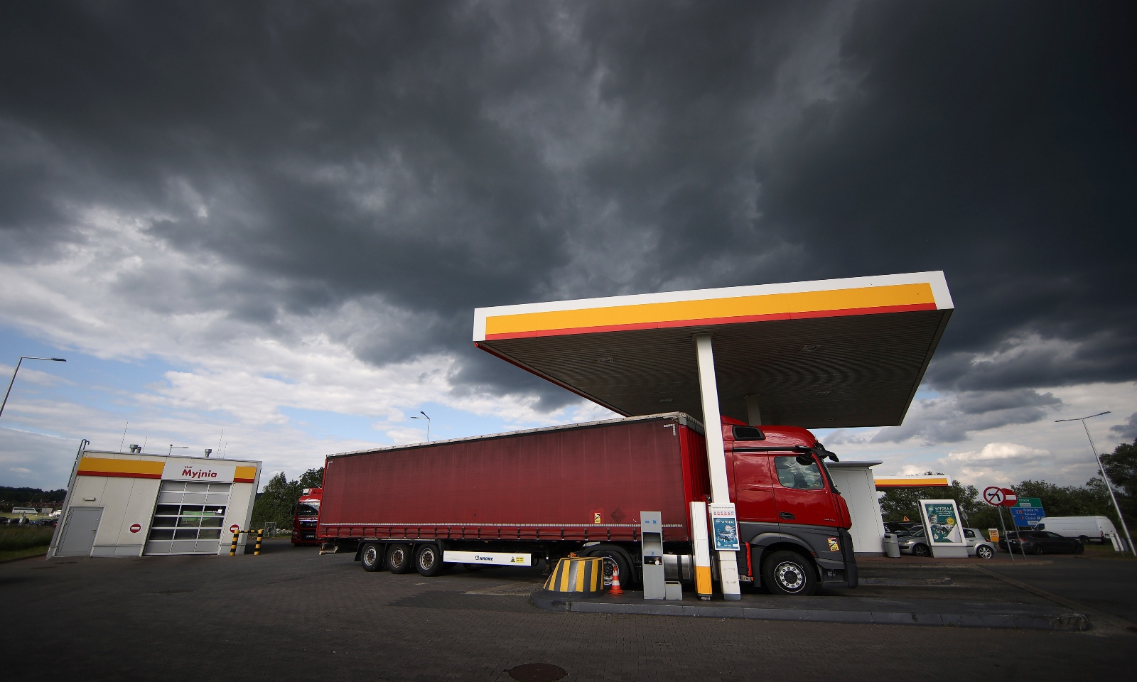 A truck parked at a Shell gas station under a dark, stormy sky.
