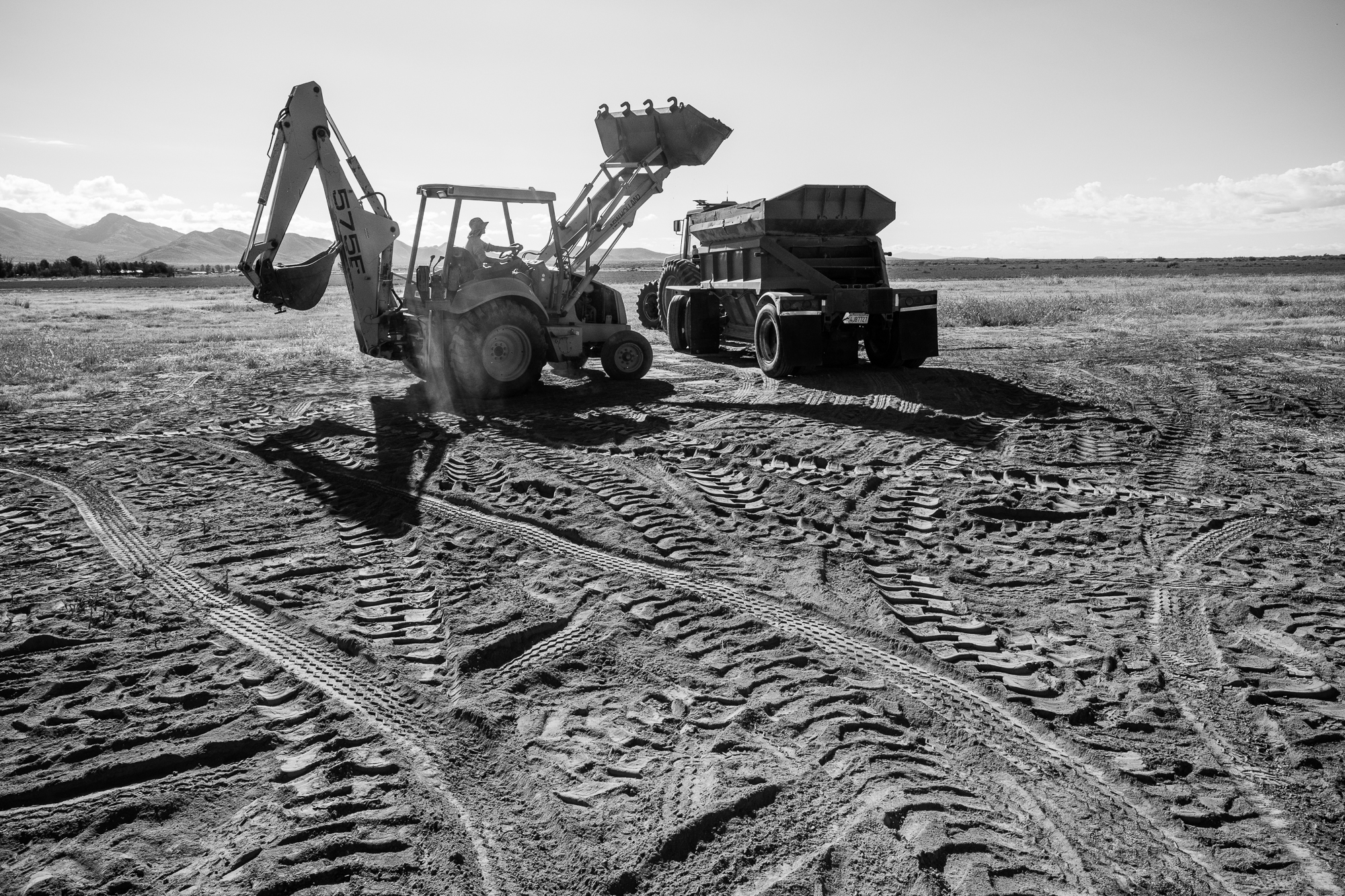 a piece of construction equipment stands on a dirt plot with lots of track marks