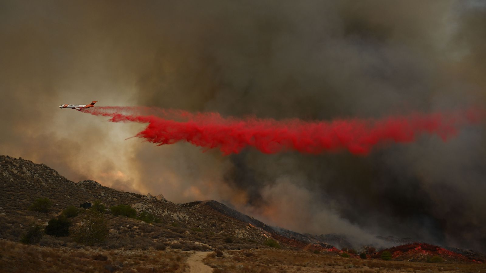 The Erickson Aero Tanker 107 MD-87 firefighting aircraft makes a drop of retardant to contain a wildfire as it approaches homes during the Fairview Fire near Hemet, California in Riverside County on September 7, 2022.