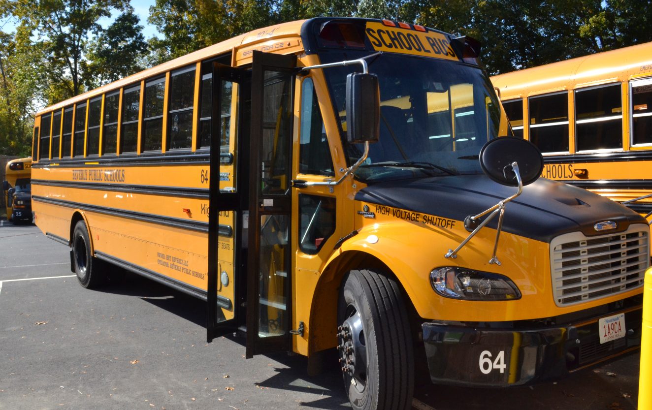 a black and yellow electric school bus sits in an outdoor parking lot