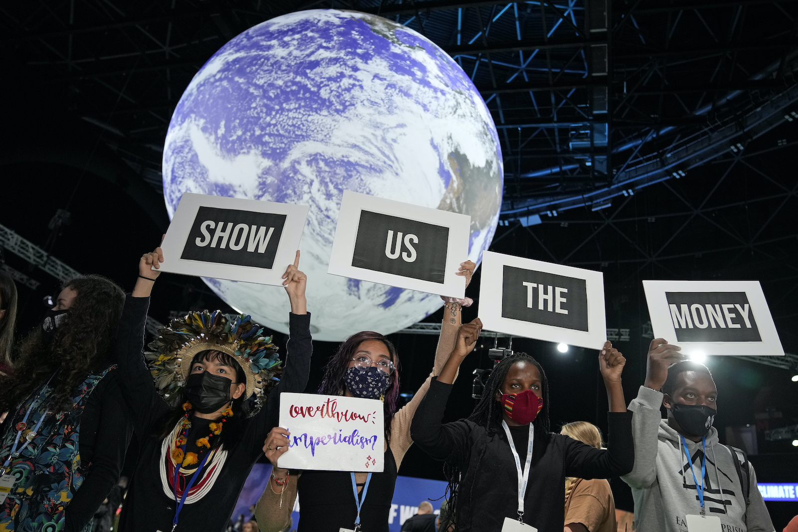 a group of people hold signs that say show us the money in front of an image of the earth