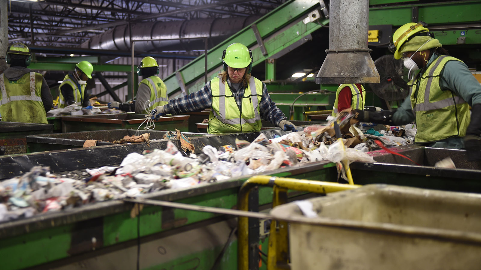 People working in waste management facility sorting through trash