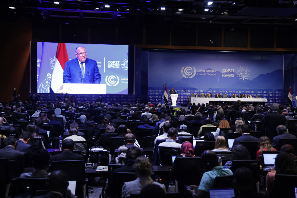 COP27 president Sameh Shoukry speaks on stage in front of crowd.